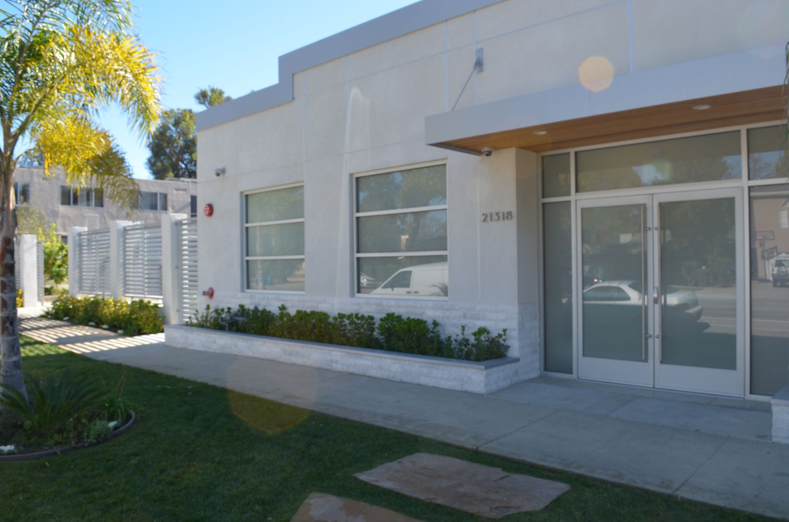 Street elevation of a completed commercial building with stacked-stone base and aluminium storefront glazing