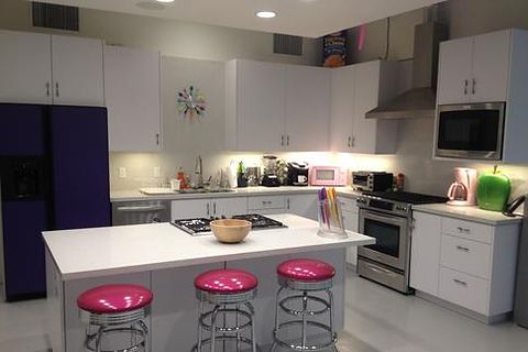 Office break room with white cabinetry, quartz island and chrome bar stools