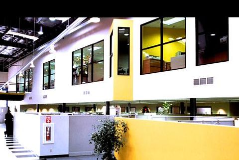 Commercial office interior with mezzanine glazing, yellow accent walls and open workstations