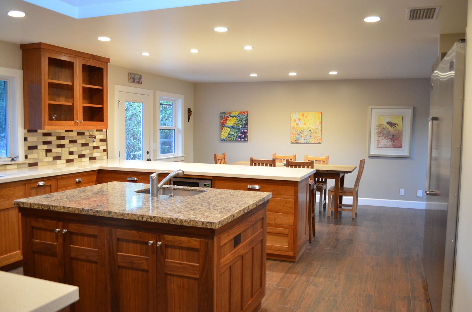 Remodeled kitchen with cherry wood cabinetry, granite island, glass-front upper cabinets and an open dining area