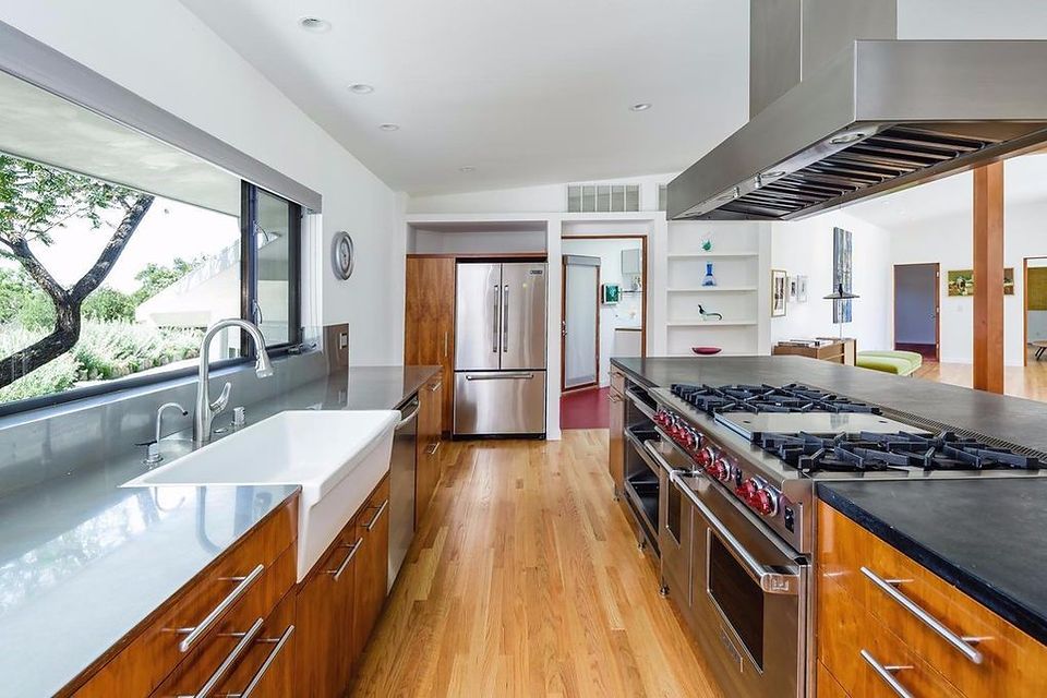 Modern remodeled kitchen with walnut cabinetry, grey quartz counters, farmhouse apron sink and a stainless professional range