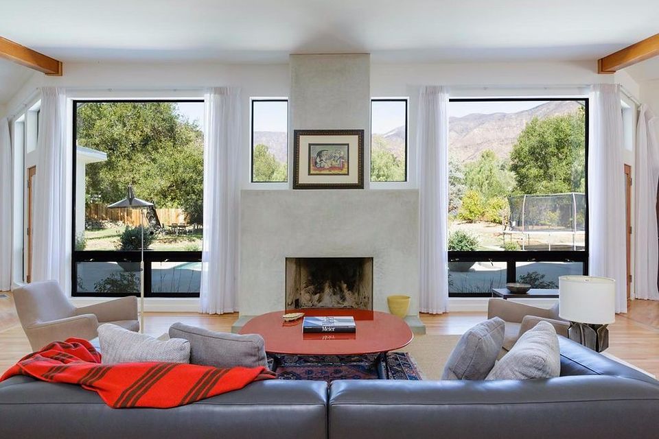 Great room facing a board-formed plaster fireplace flanked by picture windows with Ojai Valley mountain views
